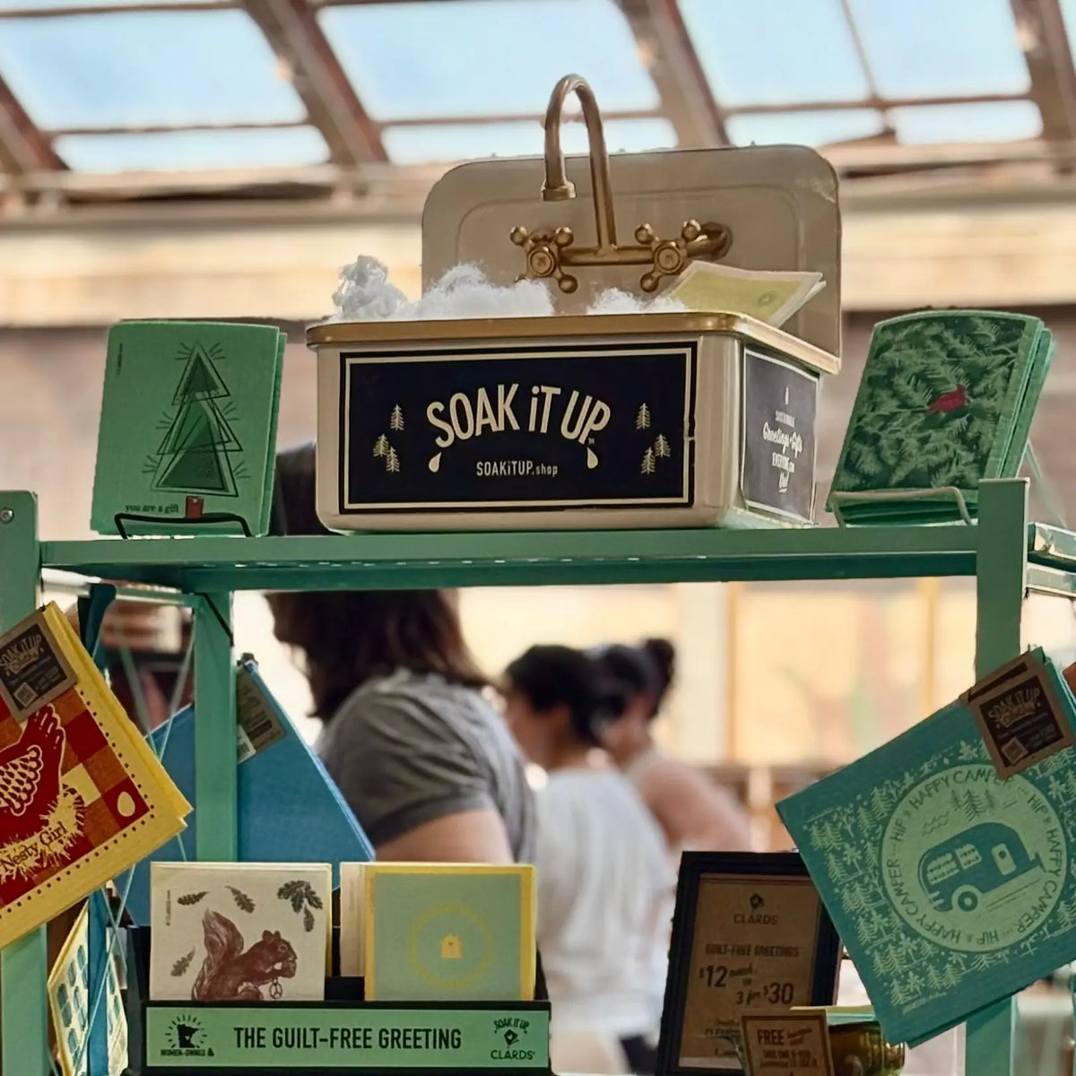 Cream-colored metal box with gold faucet handle and soak it up label featured at white bear lake holiday markets 2026