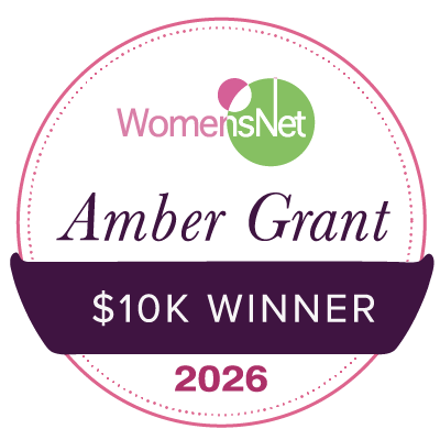 Circular amber grant badge with pink dotted border and womensnet logo recognizing carla scholz as women entrepreneurs recipient