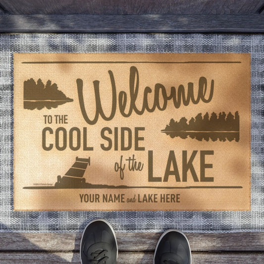 A tan welcome mat with dark brown forest silhouettes and customizable white bear lake name placeholder