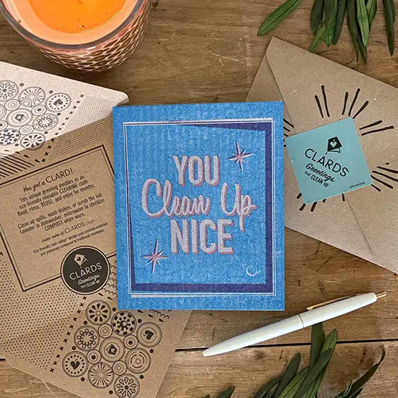 Blue textured square napkin with ’you clean up nice’ in pink and white lettering, accented by star designs.