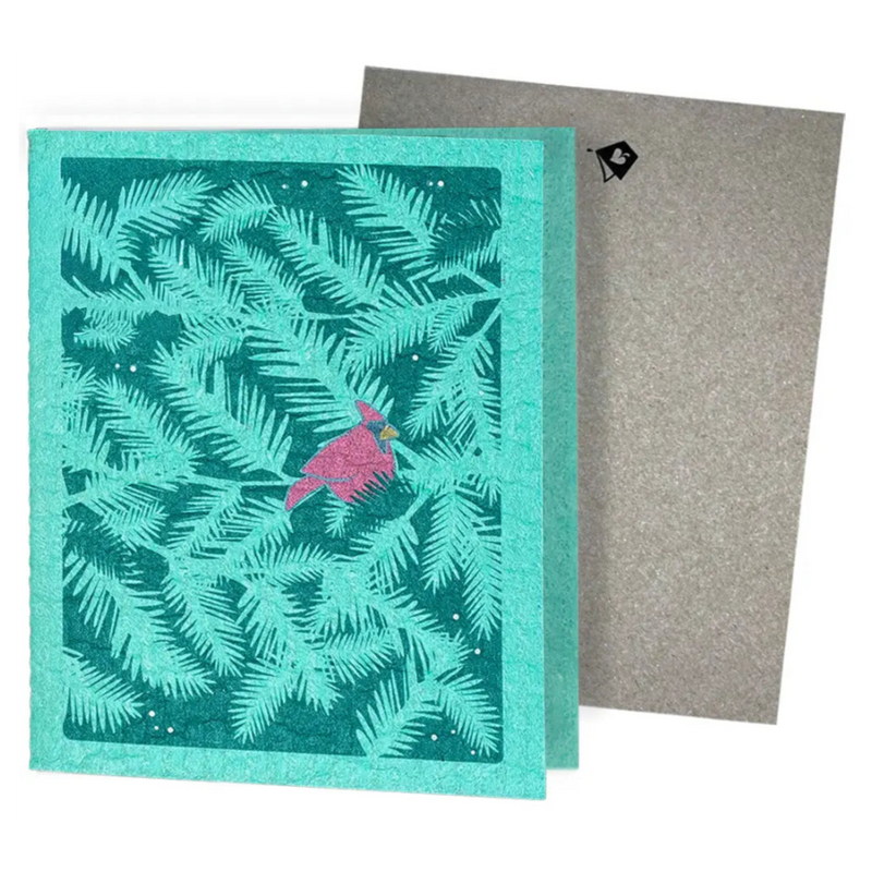 A teal textured reusable swedish sponge cloth with an embossed pink cardinal and pine branches design greeting card turns eco-friendly