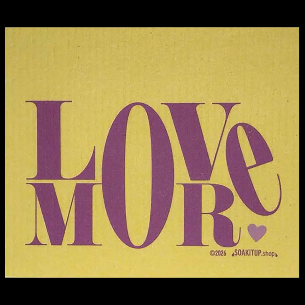 A square Swedish dishcloth featuring the word 'LOVE' in large purple serif letters over a textured mustard-yellow background, with 'MORE' in matching purple below and a small purple heart at the bottom right. Small copyright text reads '©2026 SOAKITUP.
