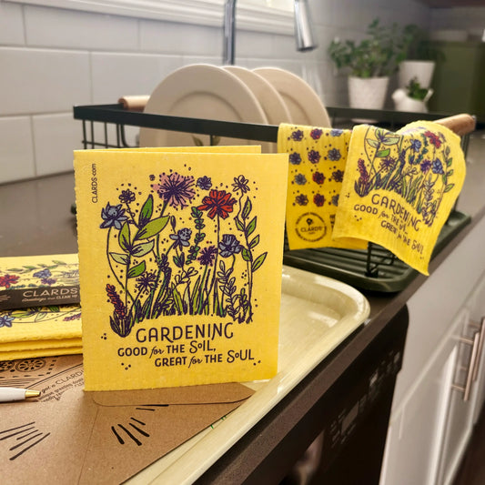Bright yellow reusable swedish sponge cloth with floral design and gardening good for the soil great for the soul text